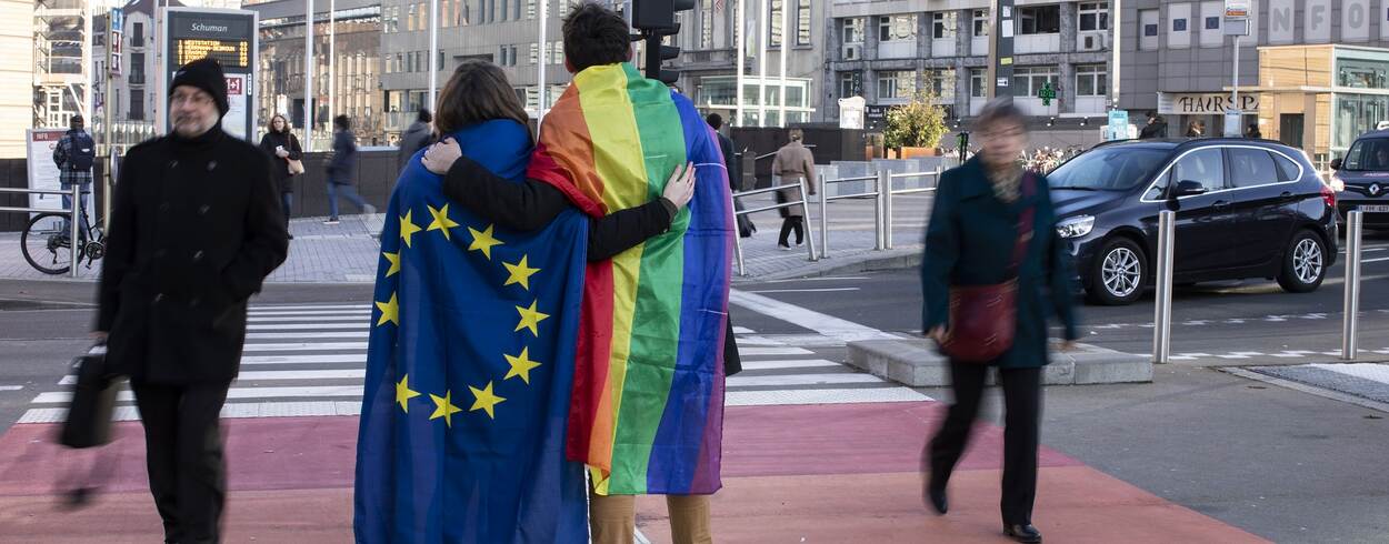 Stel met Europese en regenboogvlag omarmt elkaar op zebrapad